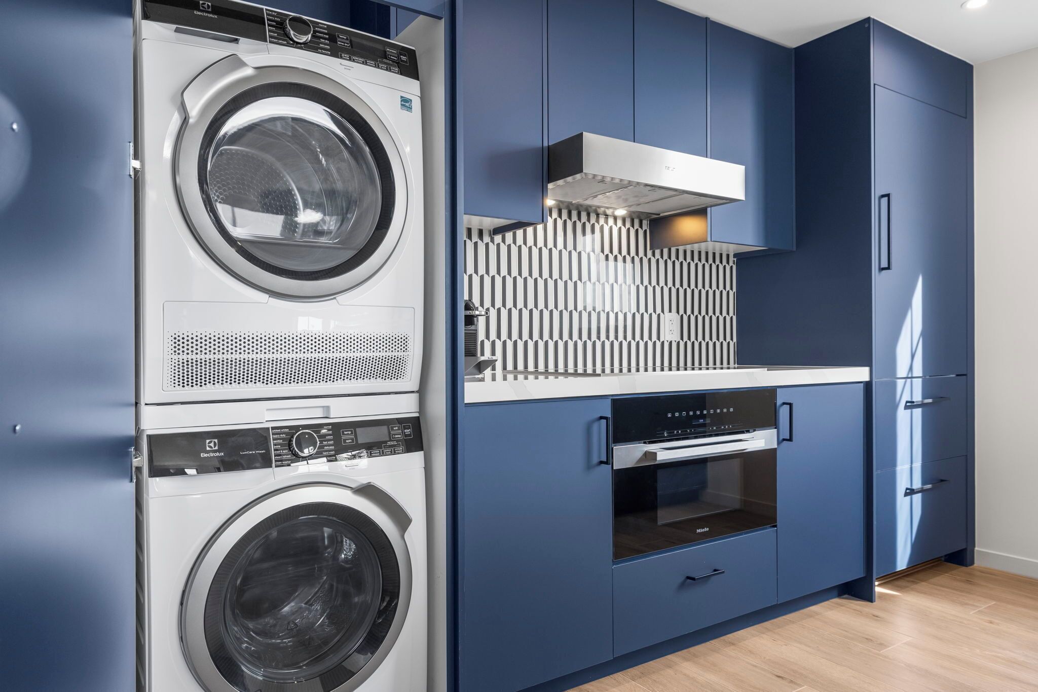 Una cocina compacta con lavadora y secadora integradas, microondas y refrigerador.