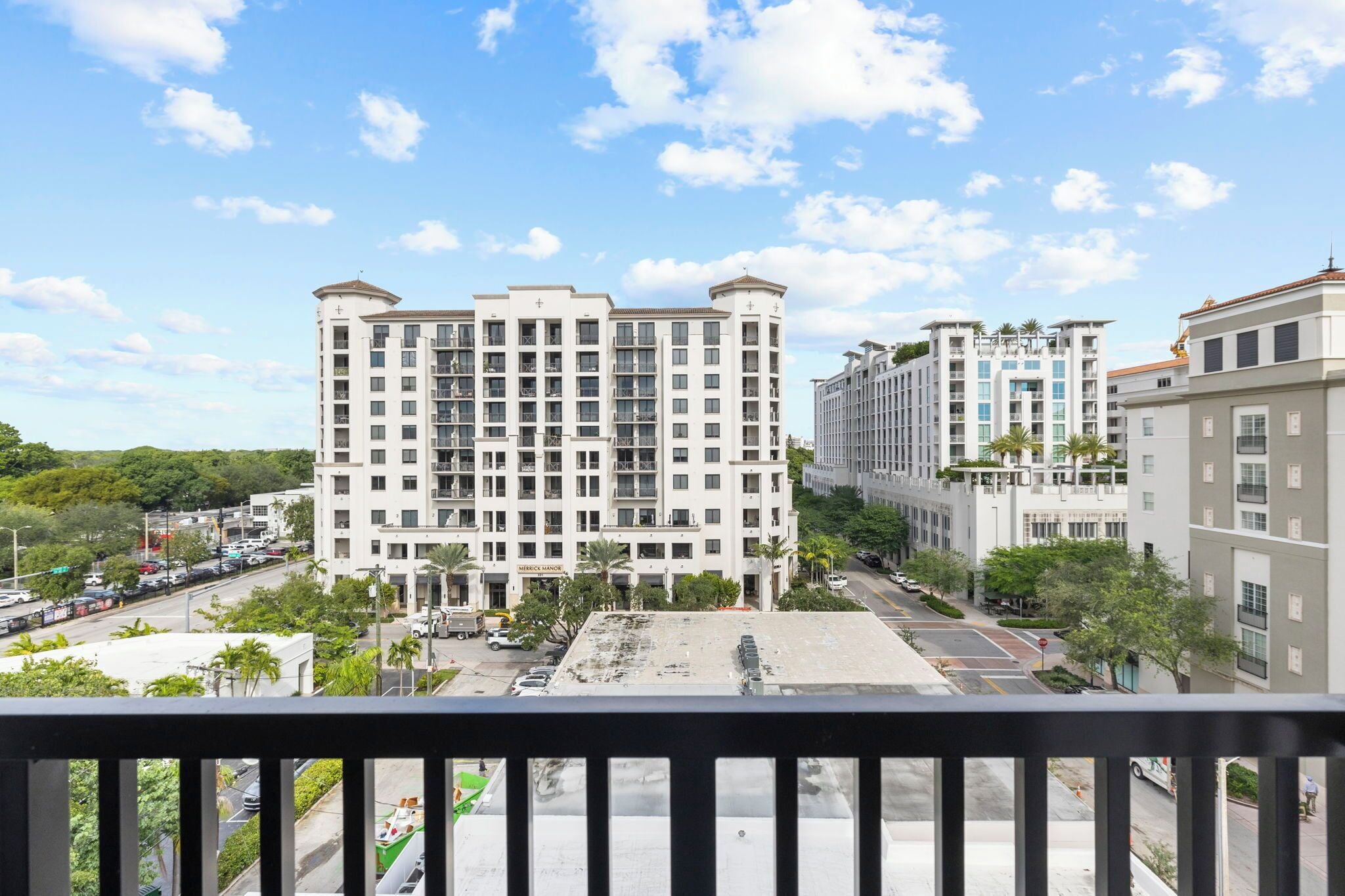 A multi-story hotel with a central courtyard, surrounded by other buildings and greenery.