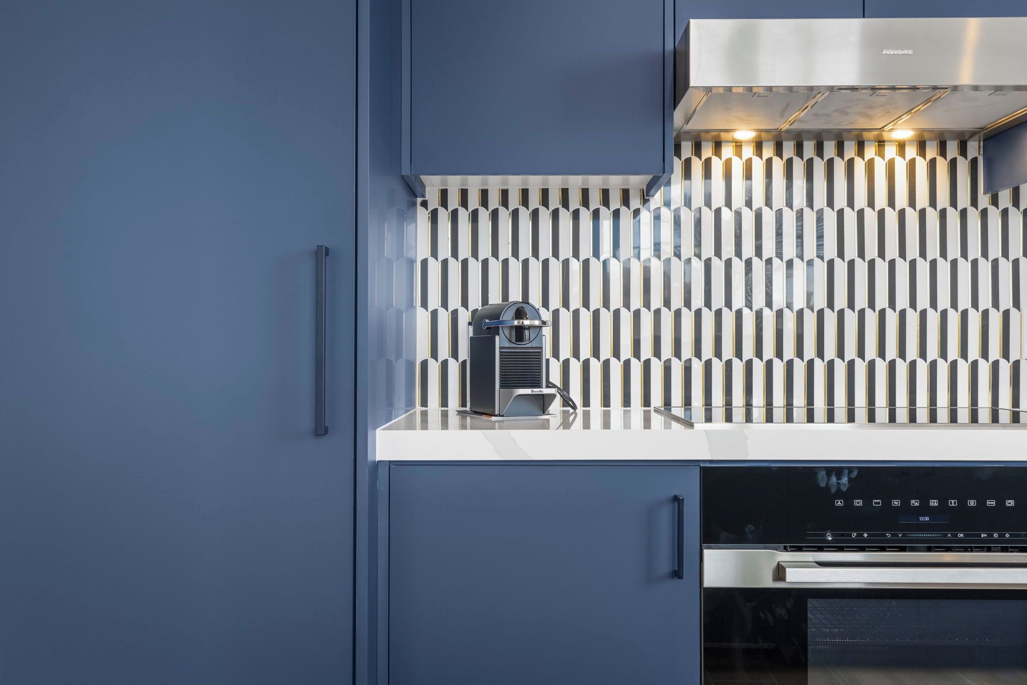 A modern kitchen with a built-in espresso machine, a stainless steel range hood, and a dishwasher.