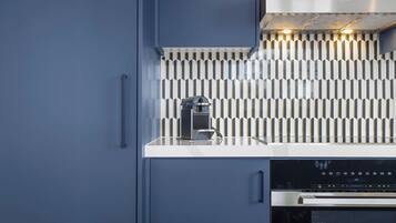 A modern kitchen with a built-in espresso machine, a stainless steel range hood, and a dishwasher.