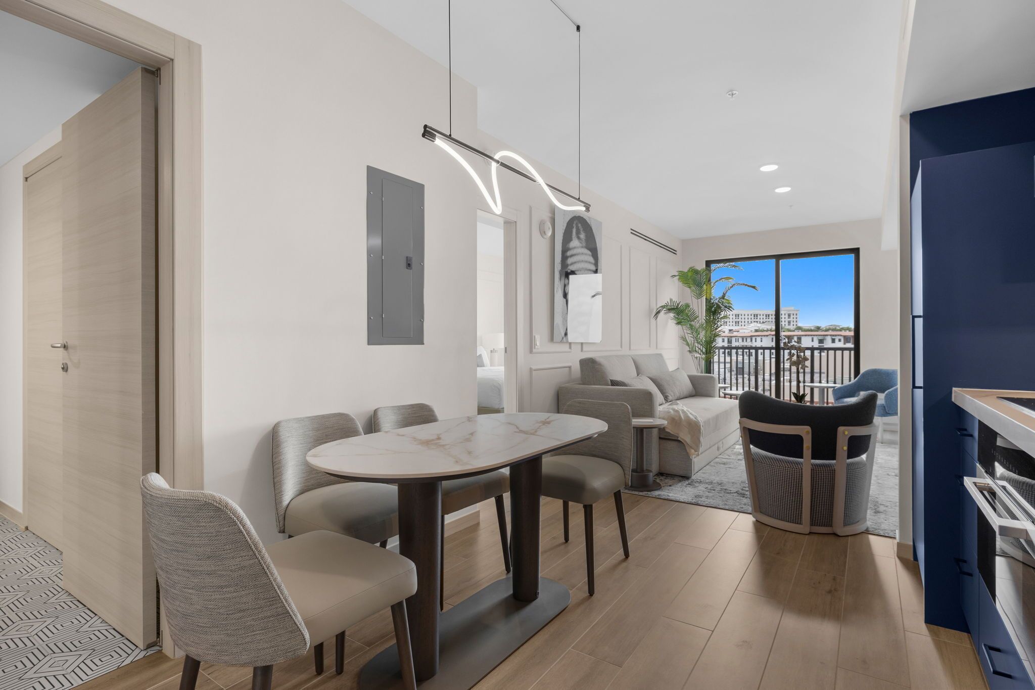 A modern living room with a dining area, a kitchen, and a balcony with a city view.