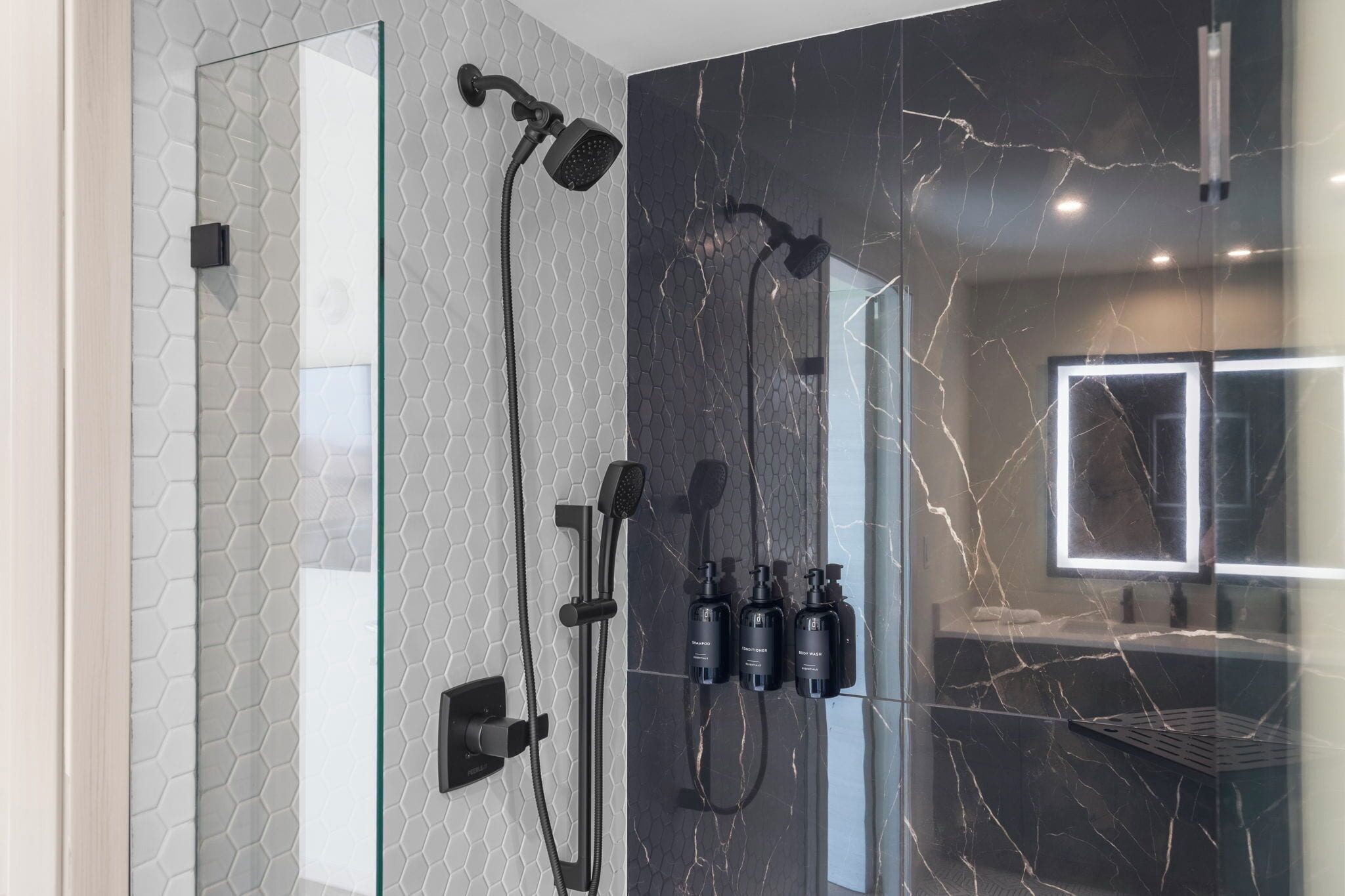 A modern bathroom with a glass-enclosed shower, a marble backsplash, and a large mirror.