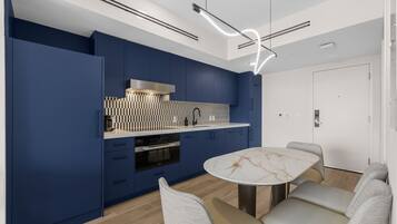 Une cuisine moderne avec des meubles bleus, un plan de travail en marbre et une table de salle à manger ronde, accompagnée de chaises.