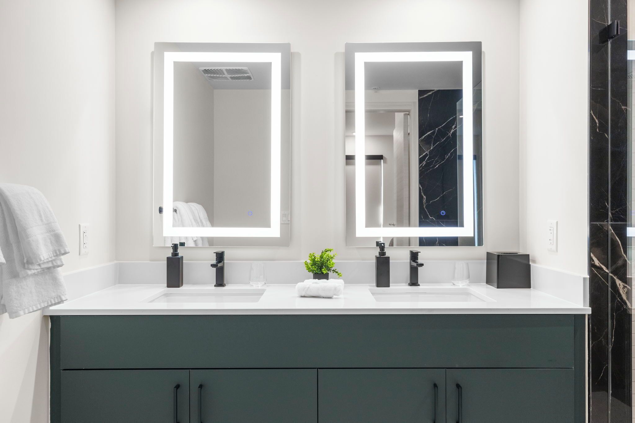 A modern bathroom with two sinks, large mirrors, and a dark-toned cabinet.