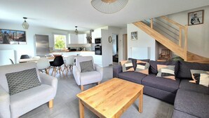 Un salon moderne avec un canapé, des fauteuils, une table basse et un escalier.