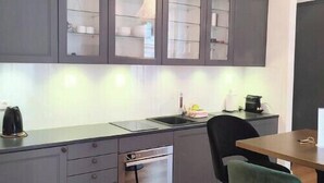 A modern kitchen with grey cabinets, a built-in oven, a sink, and a dining area with a table and chairs. - Studio in the heart of Nice, close to amenities (Nice)