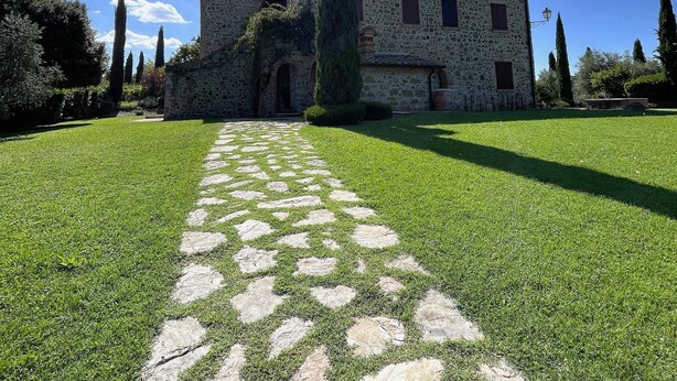 A stone building with a central courtyard, a tall cypress tree, and a clear blue sky. - Apartment 'Villa Tiberini 4' with Panoramic View, Shared Pool and Wi-Fi (Torrita di Siena)