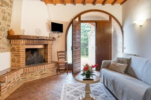 A cozy room with a fireplace, a sofa, a table, and an open door leading outside.