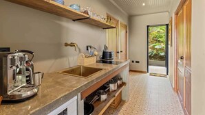 Eine kleine Küche mit Kaffeemaschine, Spüle und einer Arbeitsplatte mit Regalen.