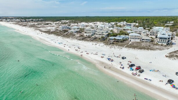 An aerial view of a beach with clear turquoise waters, a sandy shore, and beachfront properties with multiple stories and balconies. - Walk 2 Private Beach, Private Pool, Bikes, Grayton (Santa Rosa Beach)