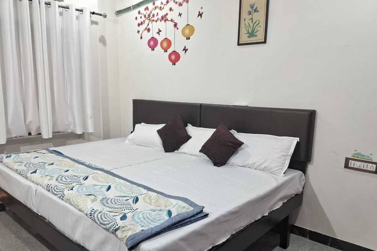 A neatly made bed with a patterned bedspread, a dark headboard, and two decorative pillows.