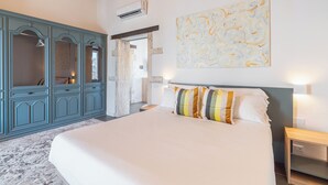 Ein Schlafzimmer mit einem großen Bett, einem blauen Kleiderschrank, einem Bild an der Wand und einer Klimaanlage.