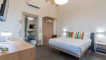 A bedroom with a bed, bedside table, and a desk with a lamp.
