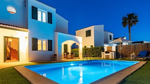 Een modern huis met een zwembad, terras en een goed verlichte entree.