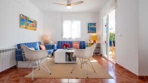 Een woonkamer met een bank, twee fauteuils, een salontafel en een plafondventilator.