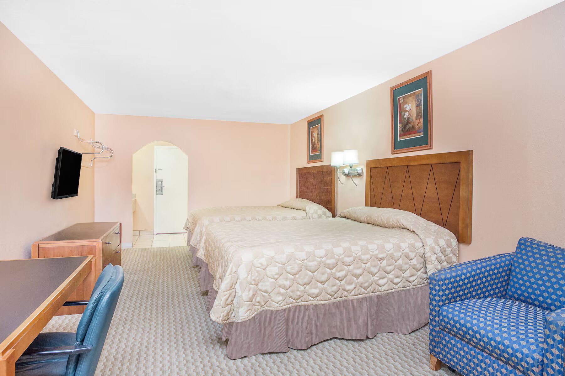 Een hotelkamer met een bed, een bureau, een stoel en een televisie.