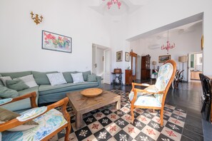 Een woonkamer met een bank, stoelen, een salontafel en een vloer met een patroon.