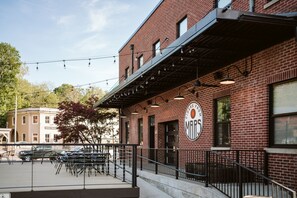 A brick building with a sign that reads "Ciders from MAPS" and outdoor seating with tables and chairs.