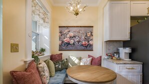 A cozy seating area with a round table, a floral painting, and white cabinetry.