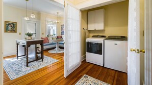 A compact kitchen with white appliances, a wooden table, and a decorative rug. - Ever After: Luxury, Romantic Unit + Walk Downtown (Staunton)