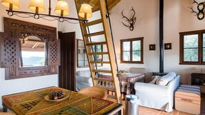 Una habitación acogedora con una mesa de madera, una escalera, un sofá y una chimenea.
