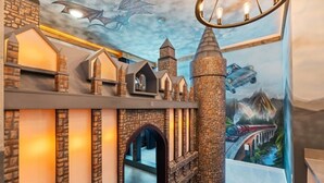 Une pièce avec un mur en briques, un escalier en bois et une fresque représentant un dragon et un château.