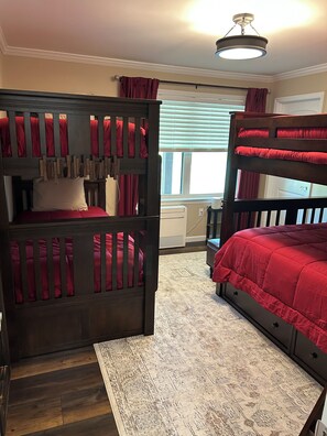 A bunk bed room with a desk and a window with curtains.