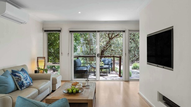 Una sala de estar moderna con un sofá, una mesa de centro y un televisor montado en la pared.