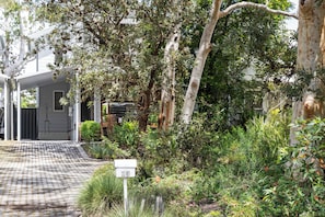 A residential property with a paved driveway, a mailbox, and lush greenery.