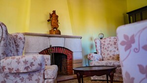 A living room with floral-patterned sofas, a fireplace, and a statue on the mantel. - Quarto Rosa Duplo Deluxe (Canal Caveira)