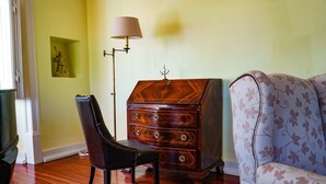 A room with a wooden dresser, a black leather chair, and a patterned sofa. - Quarto Rosa Duplo Deluxe (Canal Caveira)