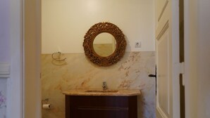 A bathroom with a marble sink, dark wooden vanity, and an ornate mirror on the wall. - Quarto Rosa Duplo Deluxe (Canal Caveira)