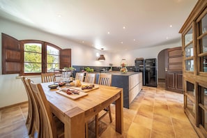 Una cocina moderna con armarios de madera, una mesa de comedor con sillas y un gran ventanal que deja entrar luz natural.