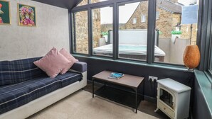Una habitación acogedora con sofá, una mesita, un calentador y vistas a un jardín y un edificio.