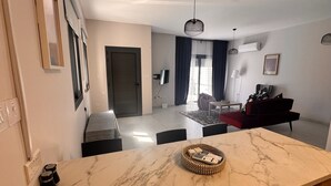A modern living area with a marble countertop, a red sofa, a grey bench, and a dining table. - Villa - Sleeps 6 - Near Local Attractions (Limassol)