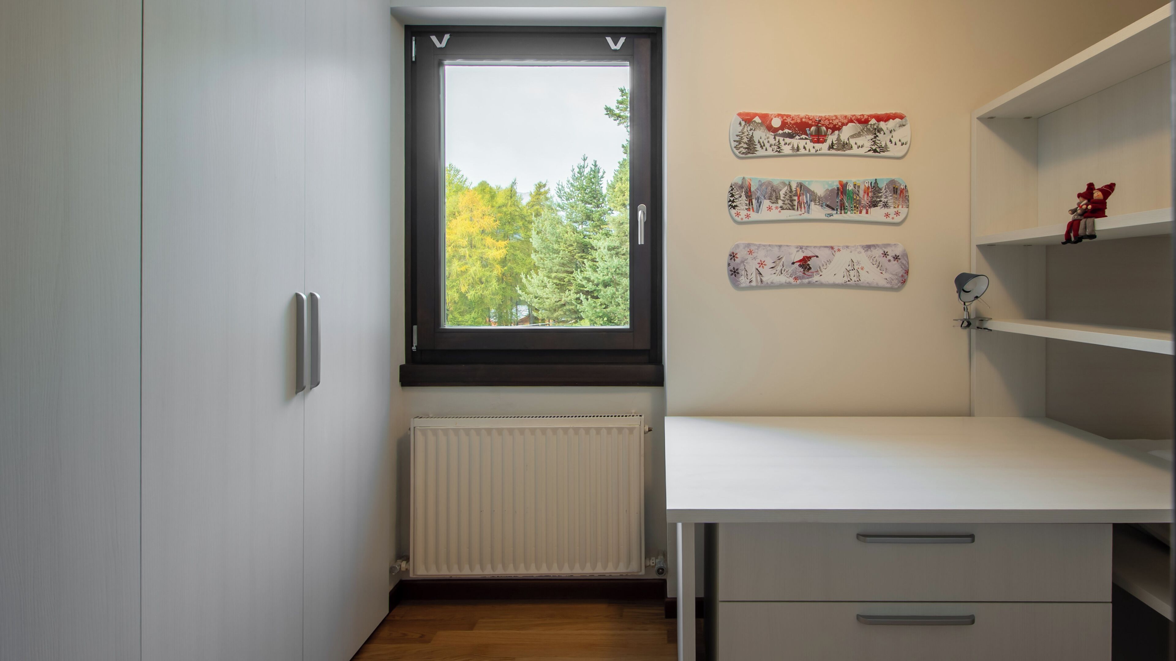 Una cocina pequeña y moderna con ventana, armarios blancos y un radiador.