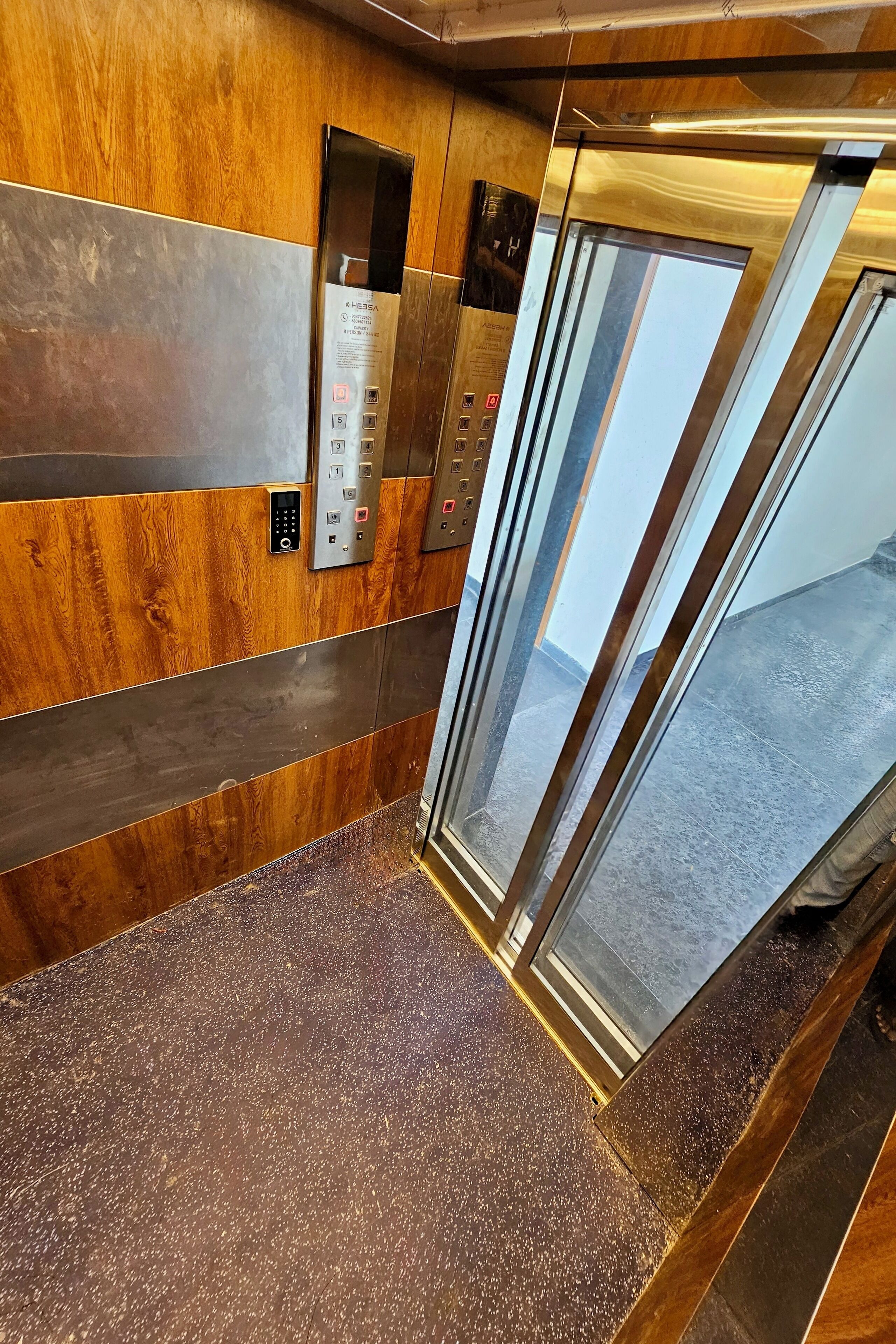 An elevator interior with wooden paneling and a control panel.