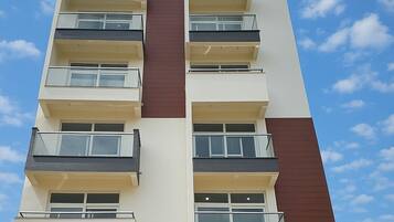 Um edifício com várias andares, varandas, janelas amplas e um céu claro.