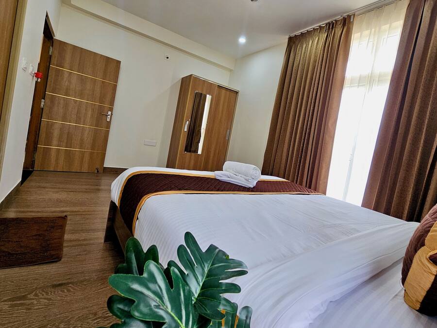 Een hotelkamer met een bed, een kledingkast, een spiegel en een raam met gordijnen.