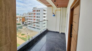 A balcony with a view of a residential area, a wooden ceiling, and a door with a handle. - TrueLife Summit Suites (Tirupati)