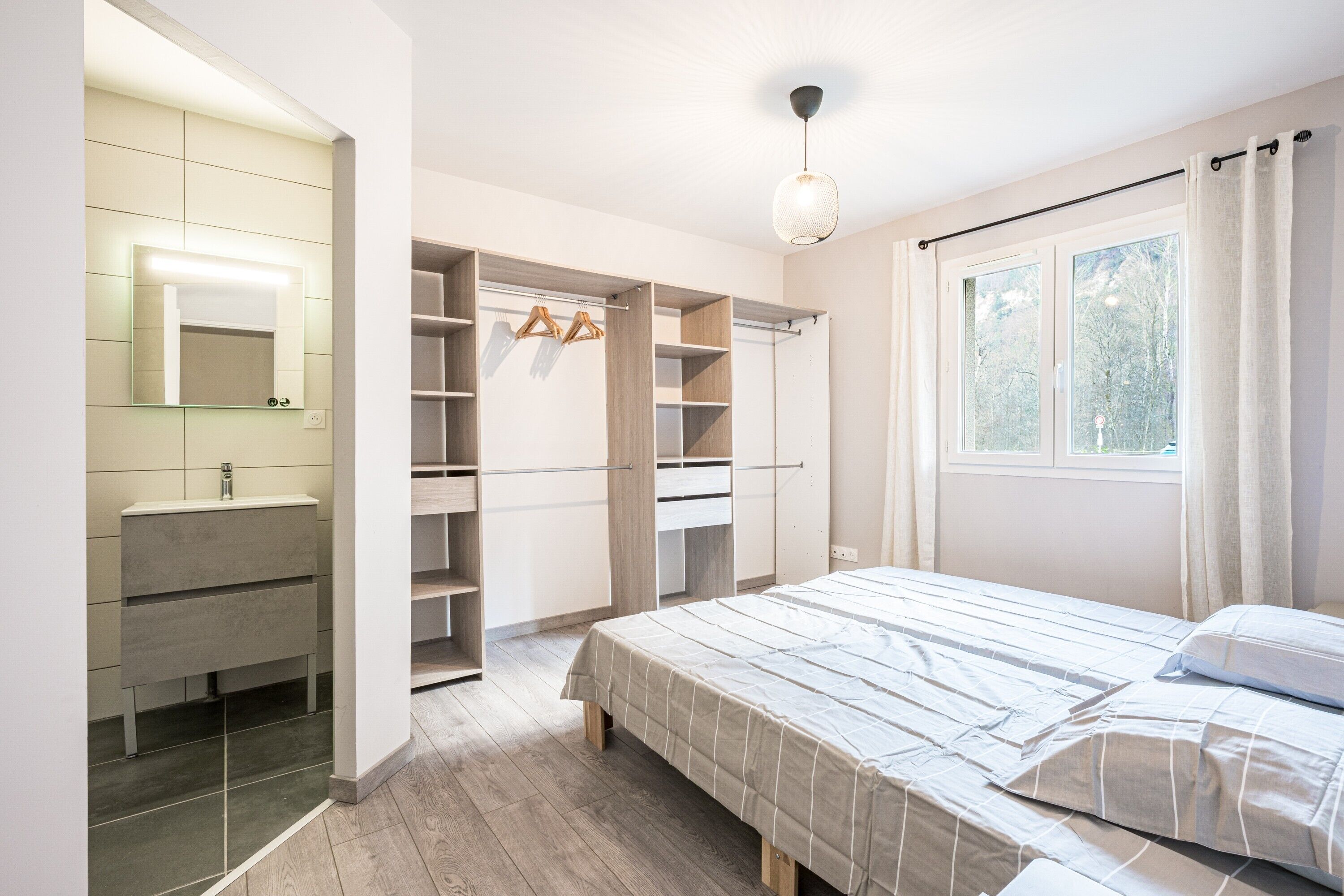 Un dormitorio con cama, armario empotrado, espejo y ventana.