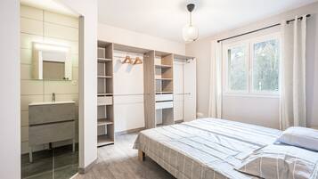 Un dormitorio con cama, armario empotrado, espejo y ventana.