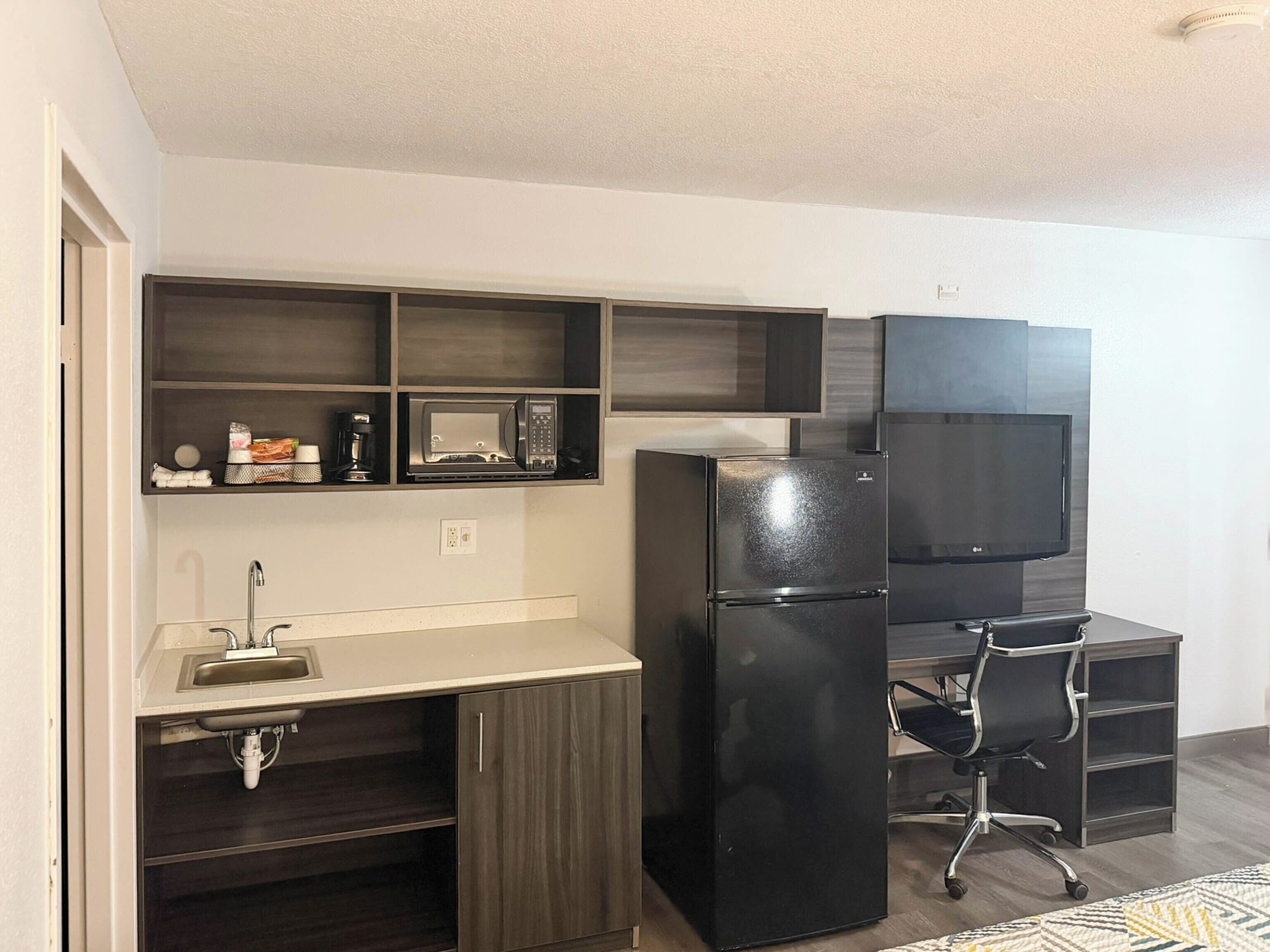 A compact kitchen with a built-in microwave, refrigerator, and a small sink.