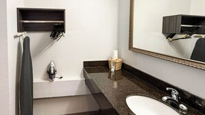 A modern bathroom with a dark marble countertop, a white sink, a large mirror, and a towel rack. - Studio 6 - Stafford, Va - Quantico (Stafford)
