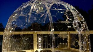 Una estructura de cúpula transparente con un muelle de madera que la rodea.