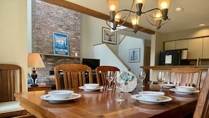 A dining area with a wooden table set for six, surrounded by wooden chairs. - NewMont Lodge- Pool, Tennis court, pool table (Killington)
