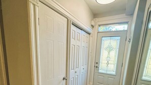 A hallway with wooden flooring, white doors, and a black doormat.