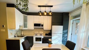 A modern kitchen with white cabinets, a central island, and a dining area with a table and chairs.