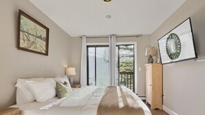 A bedroom with a bed, nightstands, a dresser, and a large window with curtains.