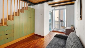 Una habitación con escalera de madera, un sofá y vistas al exterior.